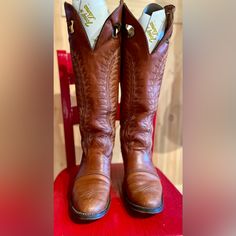 a pair of cowboy boots sitting on top of a red chair