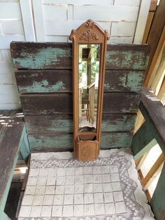 an old wooden mirror sitting on top of a table next to a bench and rug