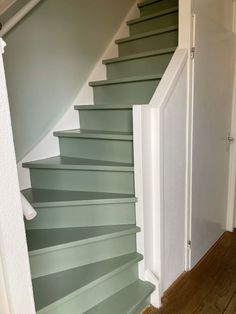 a staircase with green painted walls and wooden floors