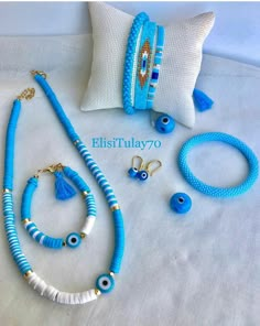 blue and white bracelets, earrings, and ring on a bed with a pillow