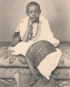 an old black and white photo of a woman sitting on a couch with her hand under her chin