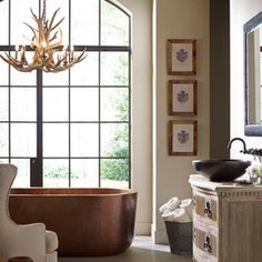 a bathroom with a tub, mirror and chandelier in it's center