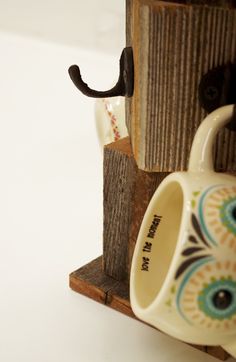 two coffee mugs are attached to a piece of wood