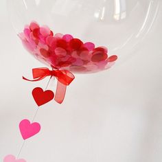 a balloon with hearts attached to it is floating in the air on a white surface