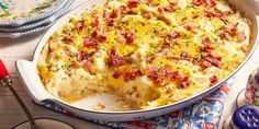 a casserole dish with bacon and cheese in it on a colorful table cloth