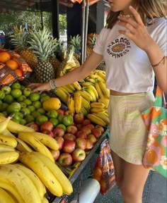 a woman standing in front of a fruit stand