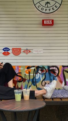 a man sitting on a bench next to a table with two drinks in front of him