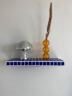 two decorative objects on a shelf in a white walled room with blue and yellow tiles