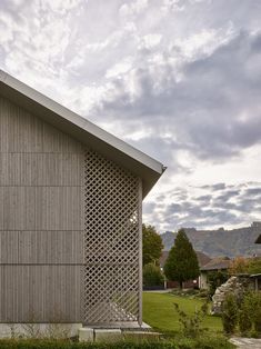 the side of a building that has a wooden structure on it's side and grass in front of it