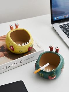 a laptop computer sitting on top of a desk next to a book and cup holder