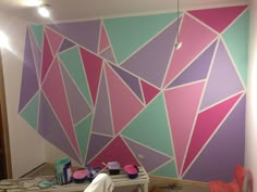 a room that has been painted with different colors and shapes on the wall, including triangles