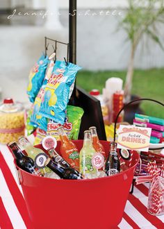 a red bucket filled with drinks on top of a table covered in candy and candies