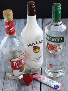 three different types of alcohol sitting on a table next to one another and strawberries