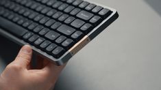 a hand holding a black and silver keyboard