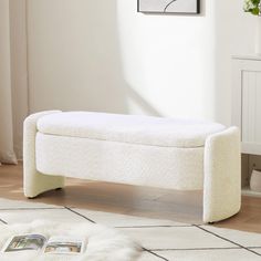 a white bench sitting on top of a hard wood floor next to a rug and potted plant