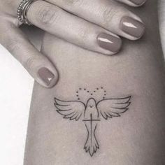 a woman's hand with a small tattoo on her left arm and the cross in the middle