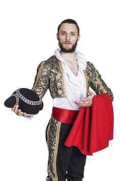 a man dressed in an elaborately designed costume holding a hat and a red cape