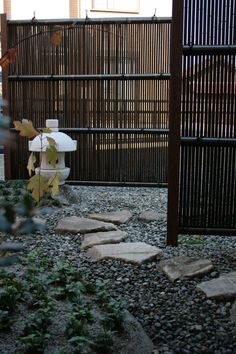 a white fire hydrant sitting in the middle of a gravel covered area next to a fence