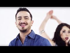 a man and woman standing next to each other in front of a white wall with their hands up