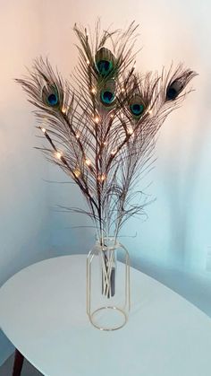 a vase filled with feathers sitting on top of a white table next to a wall