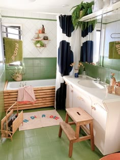 a bathroom with green and white tiles, wooden stools, and bathtub