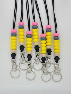 six pairs of yellow, black, and pink beaded lanyards with key chains