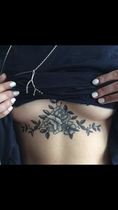 a woman's stomach with tattoos on it and flowers in the middle of her body