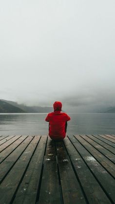 a person sitting on a dock looking out at the water