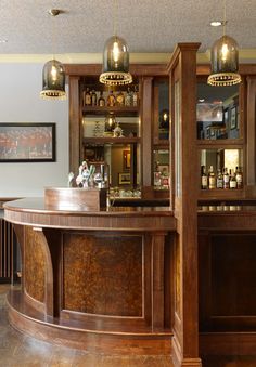 a wooden bar with lights hanging from it's ceiling in a room filled with furniture