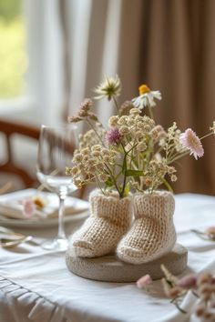 there is a vase with some flowers in it and two baby boots on the table