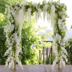 an outdoor wedding ceremony with white flowers and greenery on the side of the aisle