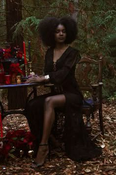 a woman sitting at a table in the woods with an afro hairdow on her head