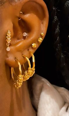 a close up of a person's ear with gold jewelry