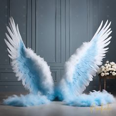 two white and blue angel wings on top of each other in front of a chair