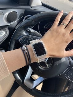 a woman is holding the steering wheel of her car while wearing an apple watch on her wrist