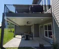 a patio with a table and chairs under a roof over looking the yard area in front of a house