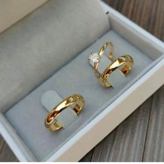 two gold rings sitting in a box on a table