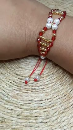 a close up of a person's arm wearing a red and white beaded bracelet