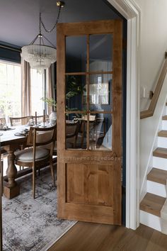 a dining room table and chairs are in front of a wooden door with glass panels