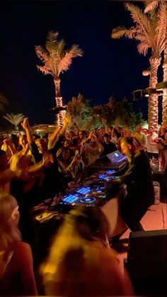 a group of people sitting at tables in front of palm trees with laptops on them