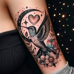 a woman's arm with a bird and heart tattoo on it