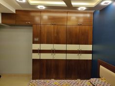 a bed room with a neatly made bed and wooden cupboards on the wall next to it