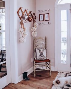 a chair in a room with pictures on the wall and a dog laying next to it