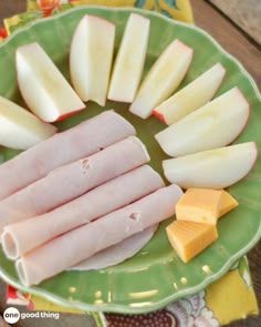 several pieces of ham and cheese on a green plate next to some slices of cheese