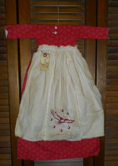 a red and white dress hanging on a wooden chair with shutters in the background