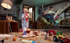 two children playing with toys on the floor in a living room filled with clutter