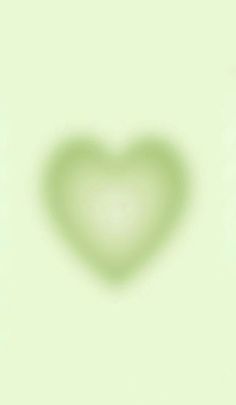 a green heart shaped object on a light green background with the shadow of a teddy bear