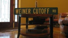 a sign that reads wiener cutoff rd sitting on top of a wooden table in front of a window