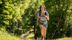 a woman with a backpack is running in the woods