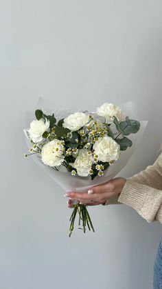 a woman holding a bouquet of white flowers